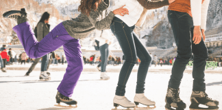 three friends ice skating together outside