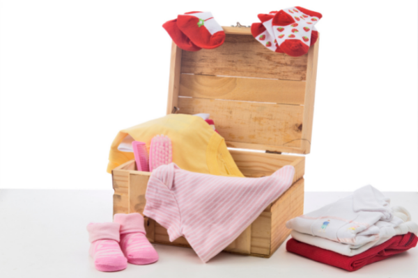 pink and red baby clothes draped over a box