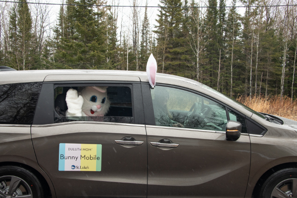 Person in Easter Bunny costume waving out of a van window
