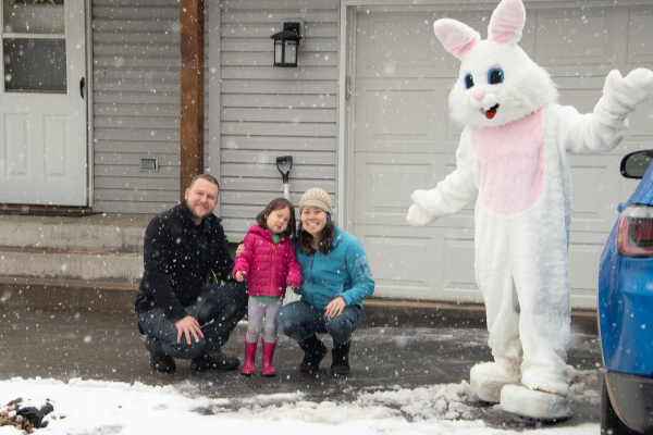 person in a Easter Bunny Costume standing in front of a house posing with a family