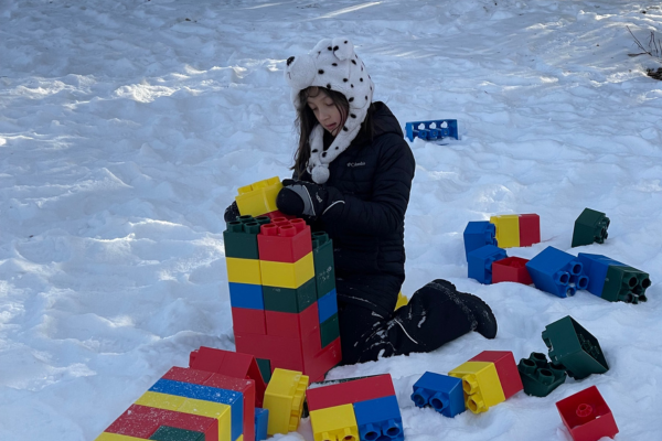 kid building with big colorful blocks outside in the winter snow
