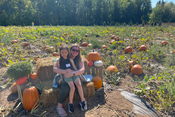 mother and daughter sitting on hay bales in a pumpkin patch on Farmer Doug's farm
