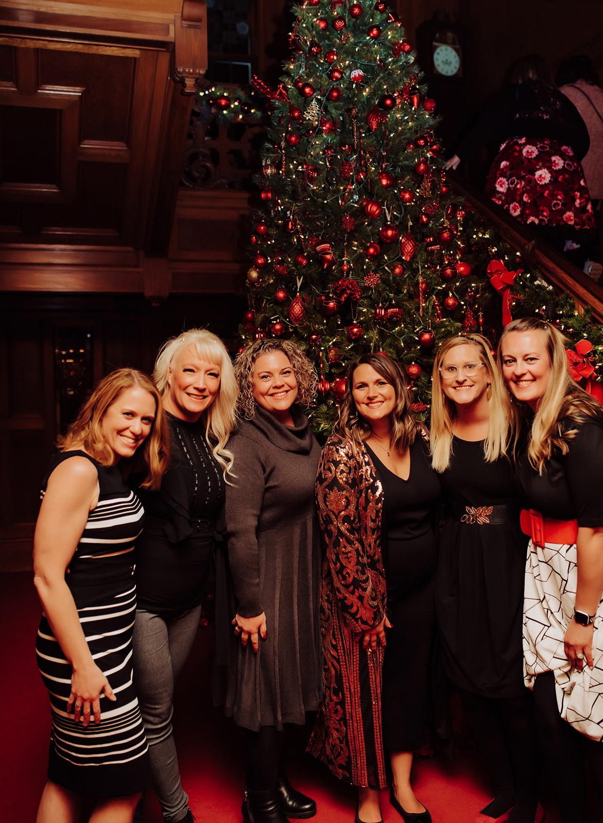 6 moms dressed up standing in front of a Christmas Tree