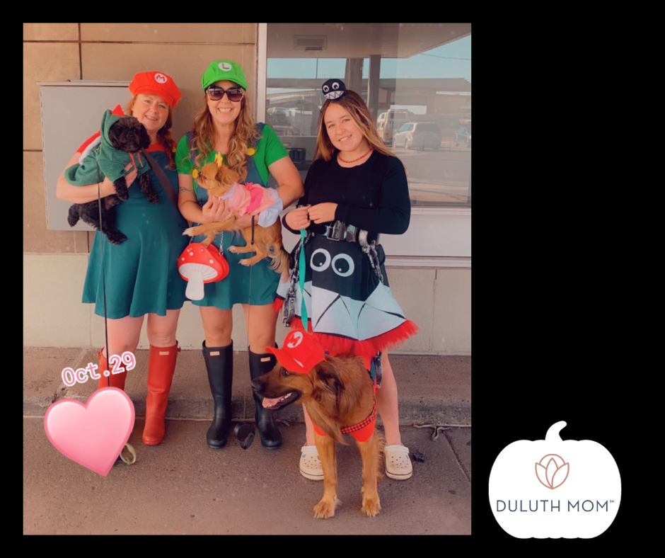 Three ladies dressed as Mario, Luigi and another SuperMario character holding dogs and mushrooms